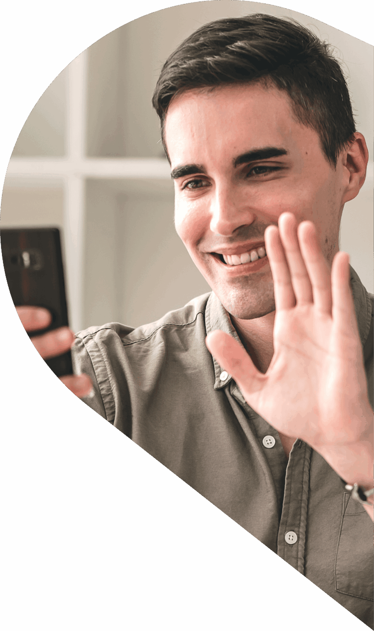 Smiling man selfie-waving at the camera while holding a phone, with a bold red curved background.