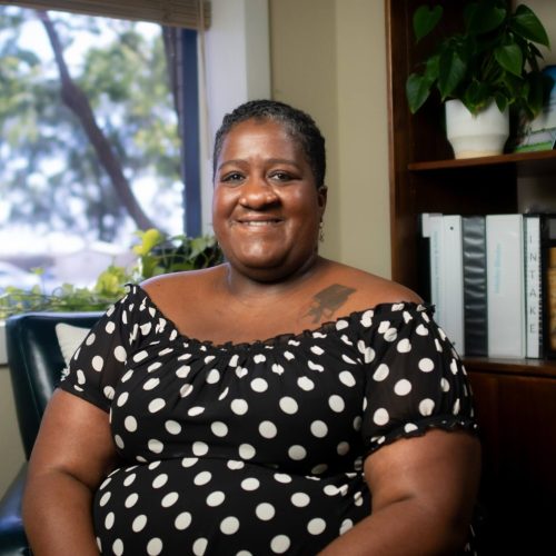 Stacia Ponce, smiling woman in polka dot dress, reviewed expert, portrait in office setting, natural light.